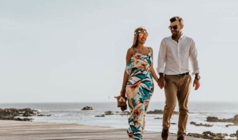 un homme et une femme marchant sur la plage main dans la main