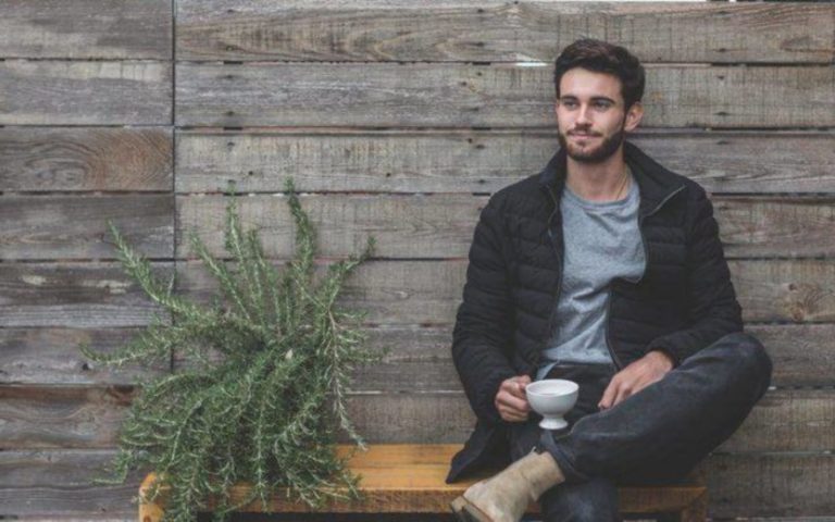 un homme est assis a boire du cafe et a regarder la distance