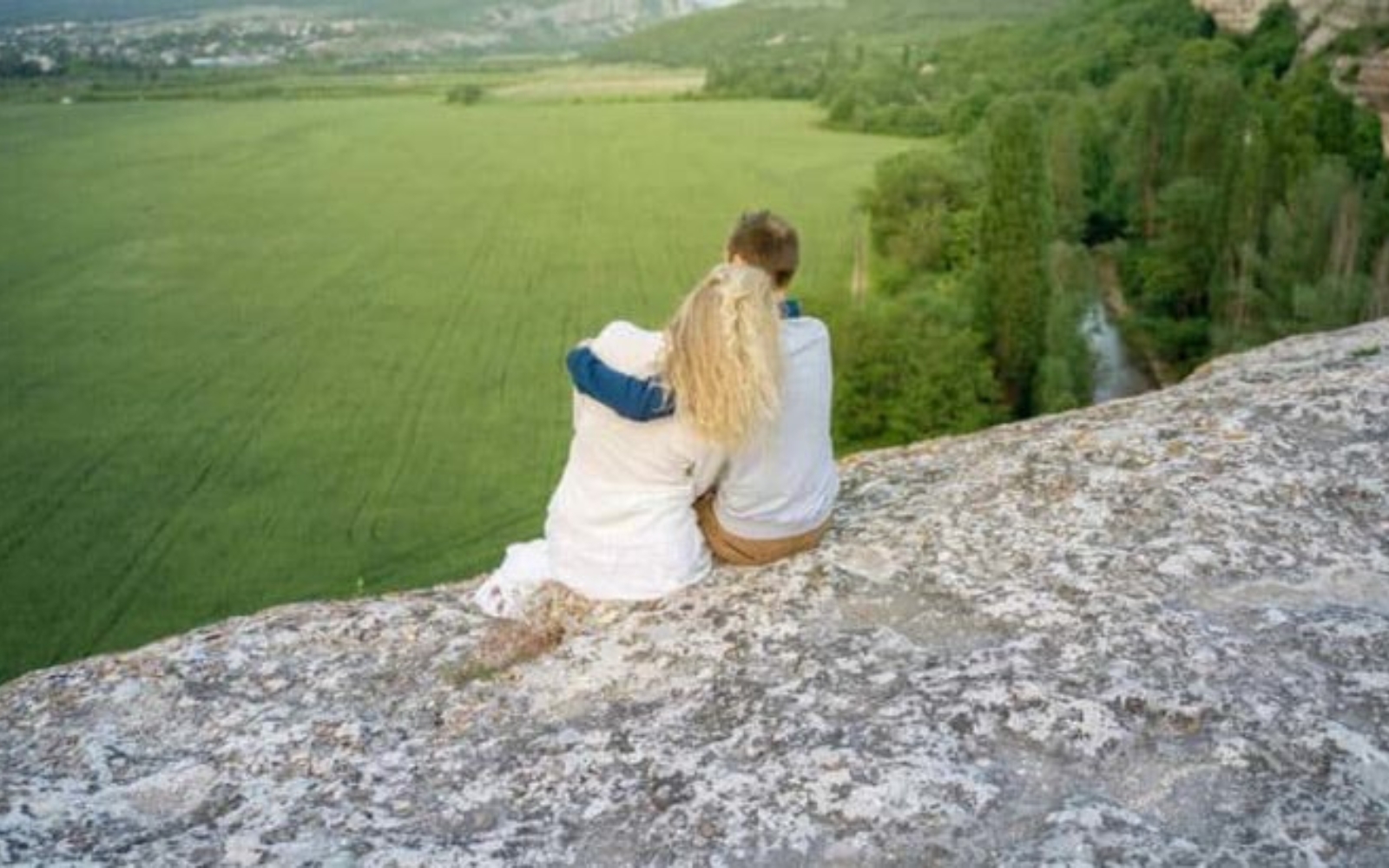 un homme et une femme sont assis sur un rocher