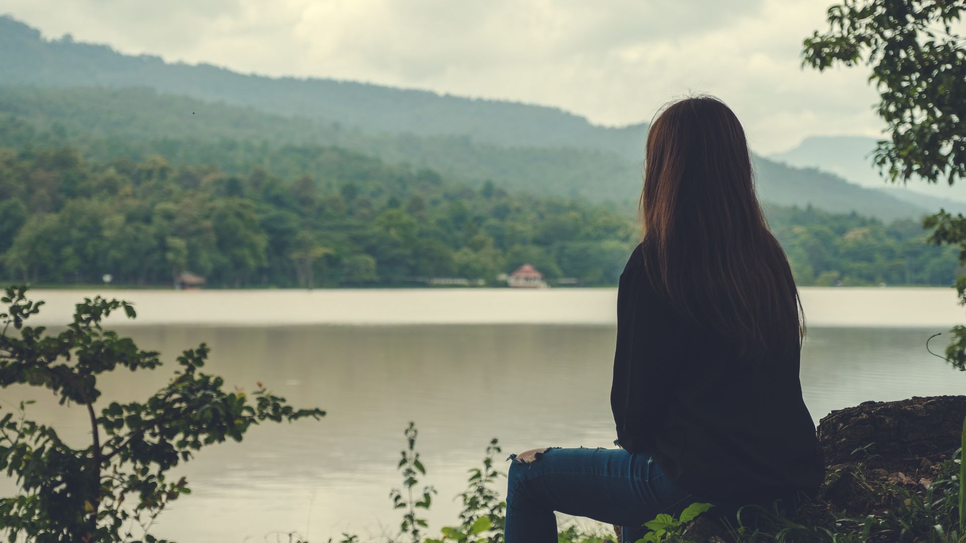 la fille est assise sur une pierre et regarde la rivière