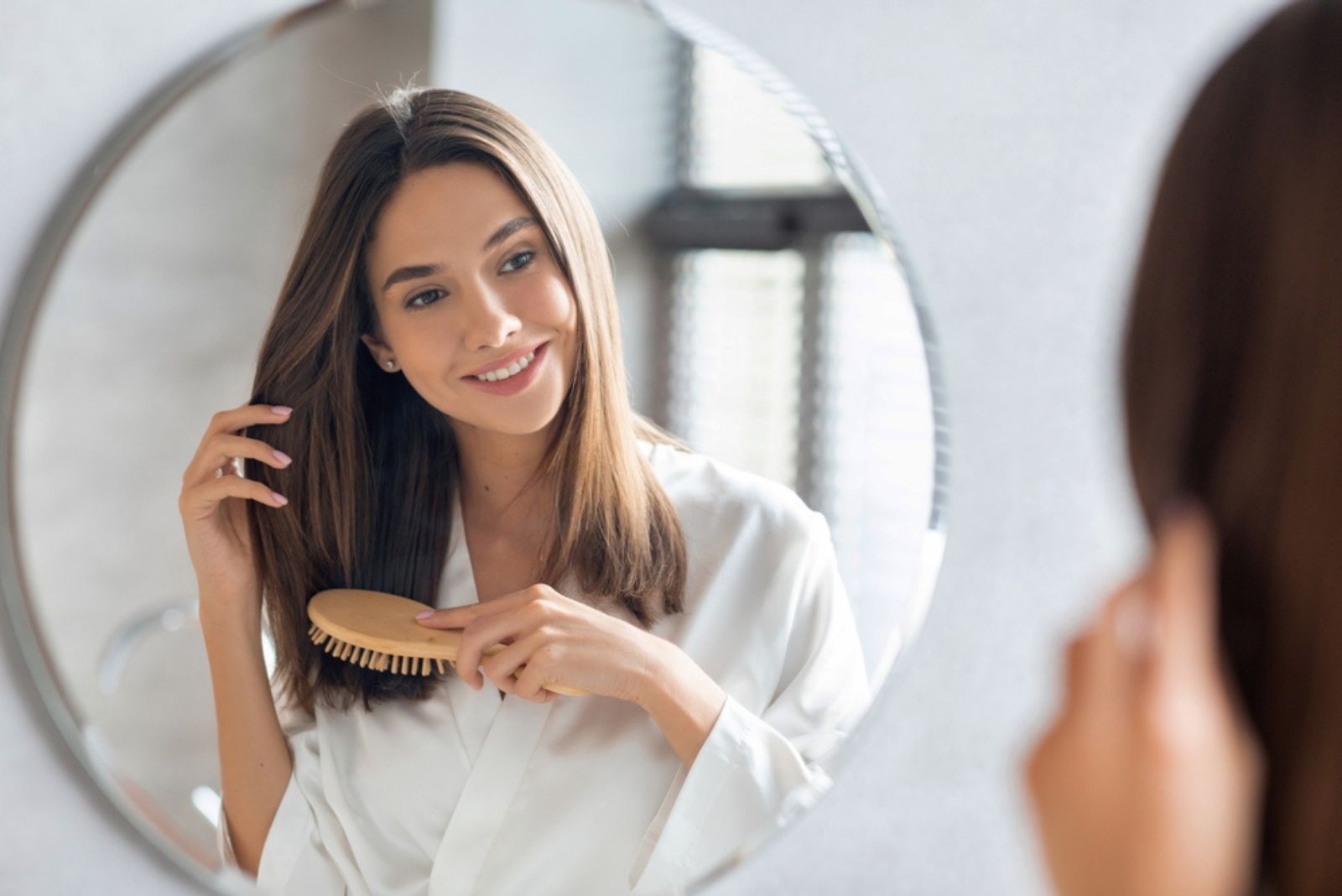 femme se brossant les cheveux devant le miroir