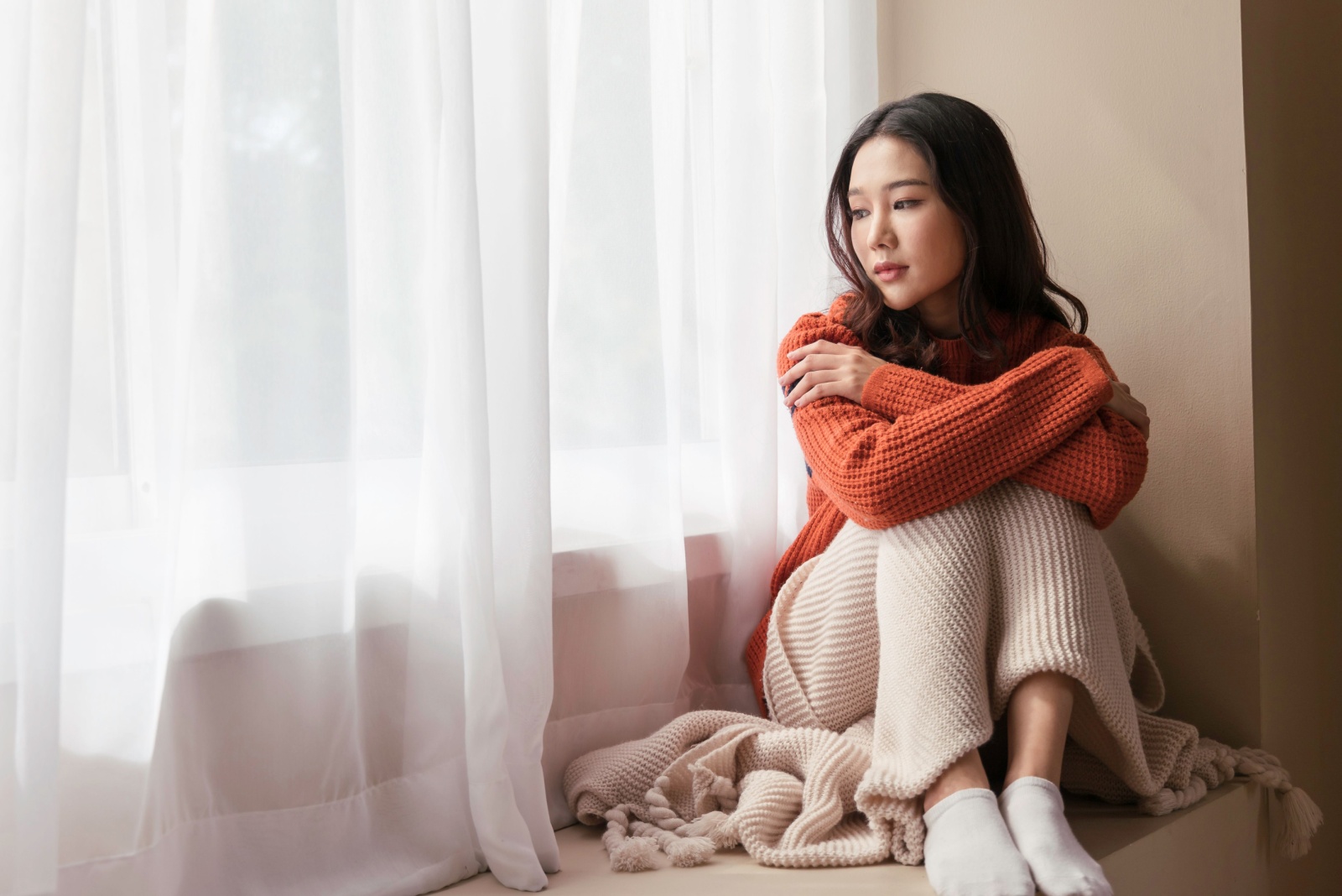 Une femme est assise a cote dune fenetre