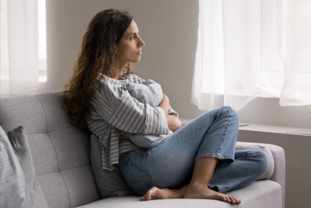 fille pensive assise sur le canapé