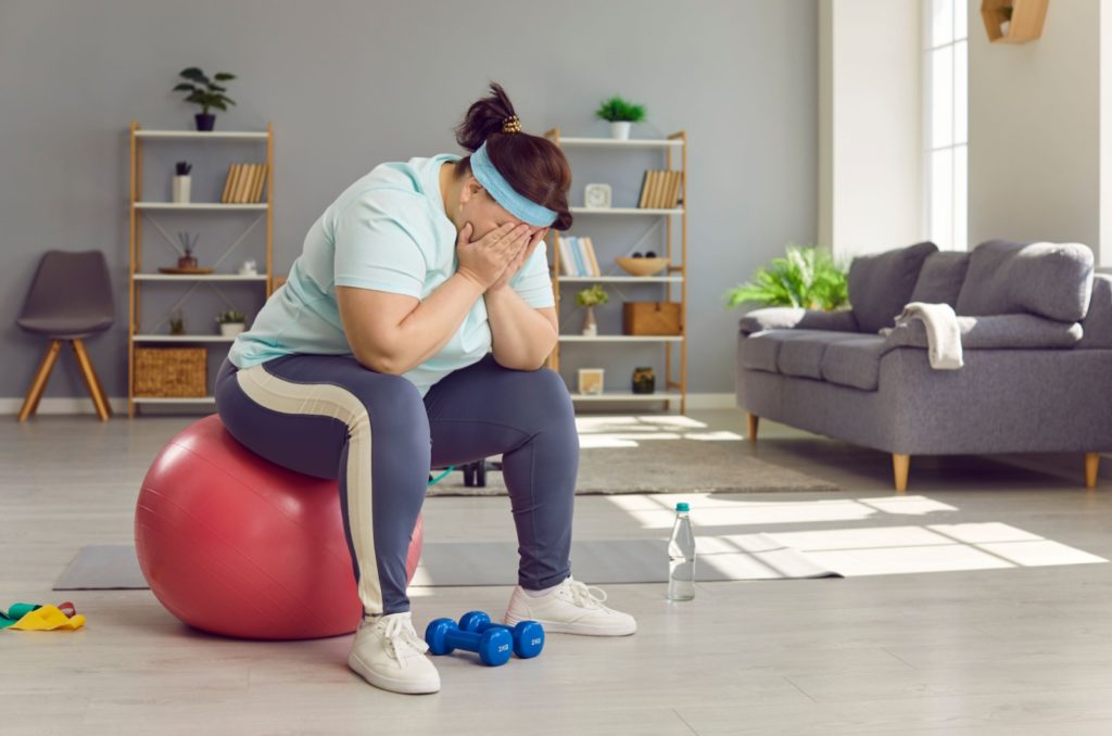 grosse femme assise sur un ballon d'exercice déçue