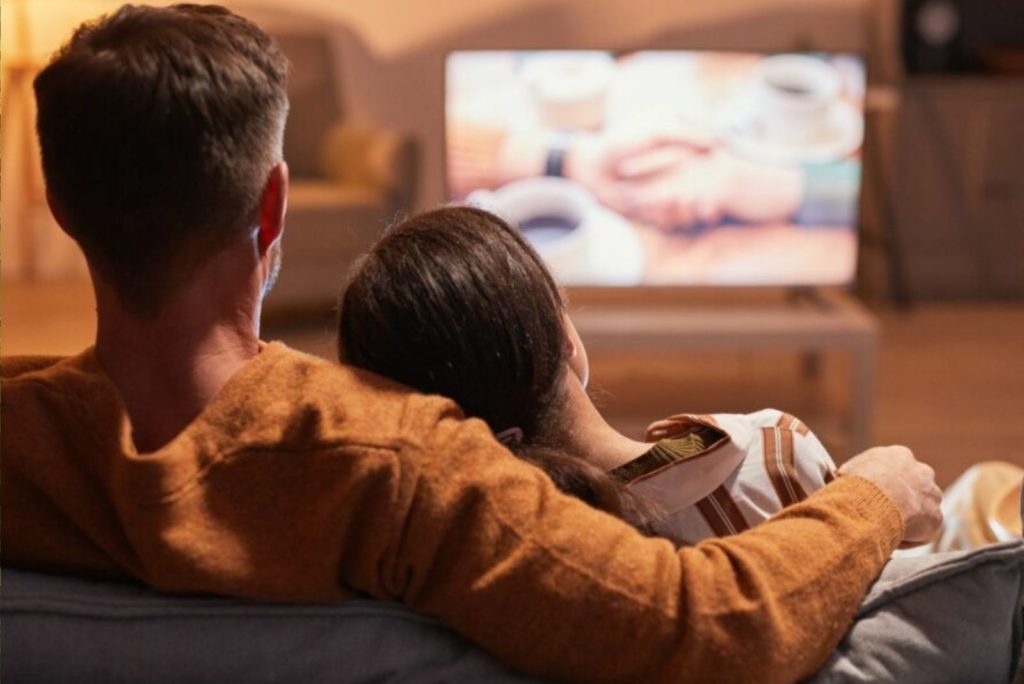 homme et femme s'embrassant devant la télévision