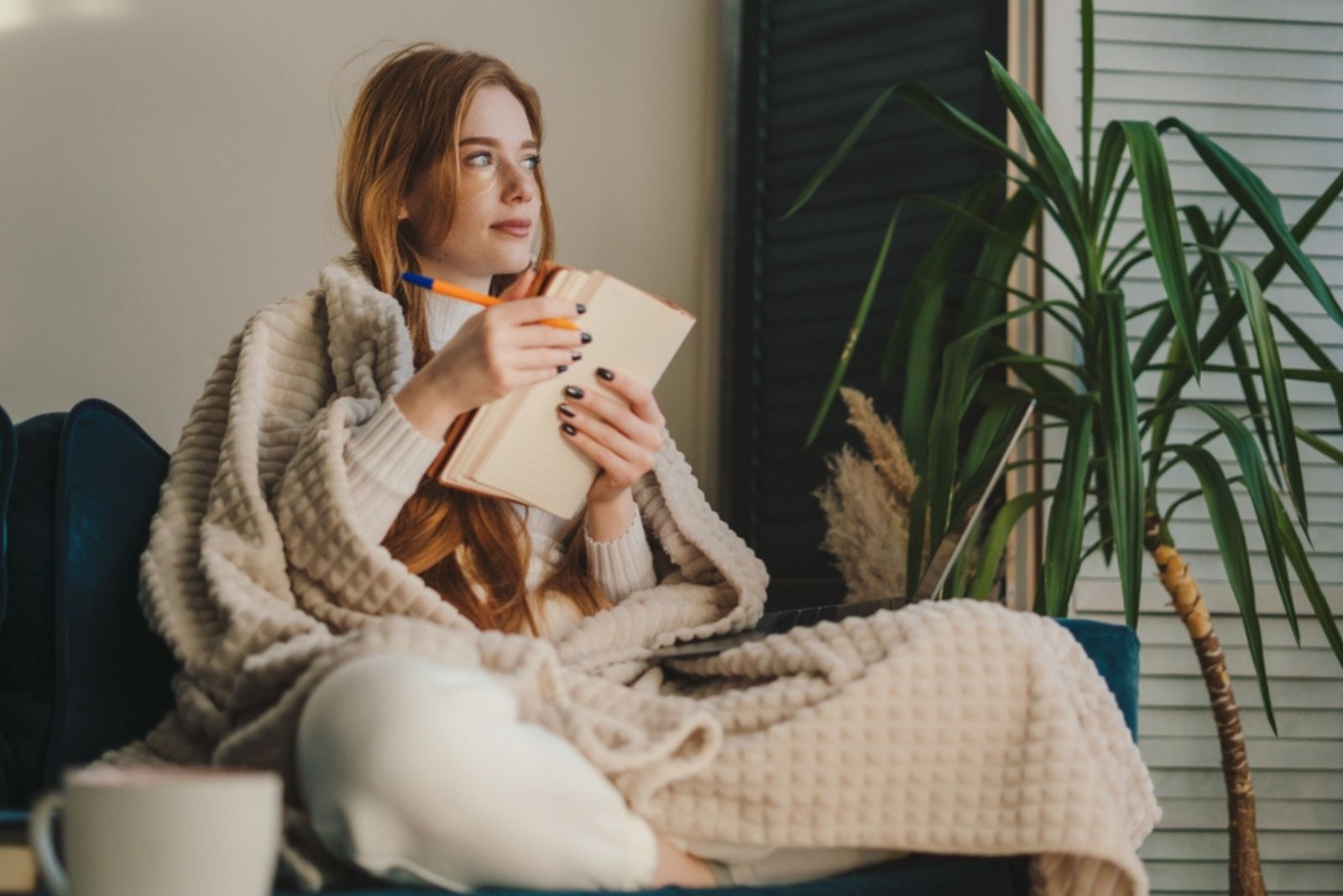 jeune femme assise sur un canapé recouvert d'une couverture