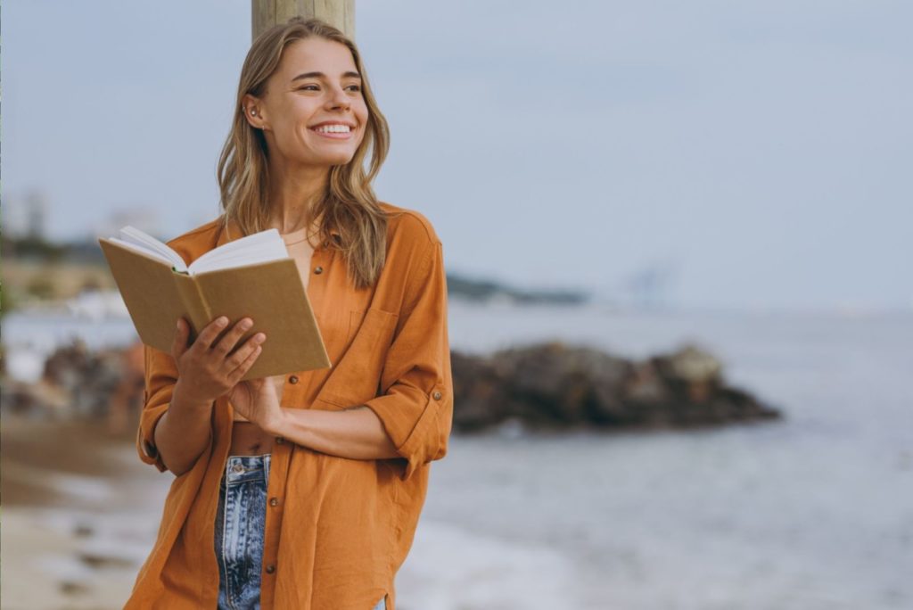 la jeune fille est debout, appuyée contre un arbre avec un livre