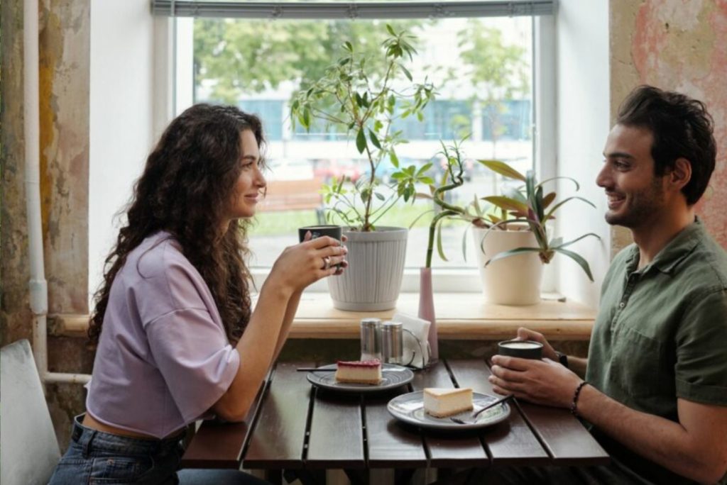 un homme et une femme sont assis l'un en face de l'autre dans un café