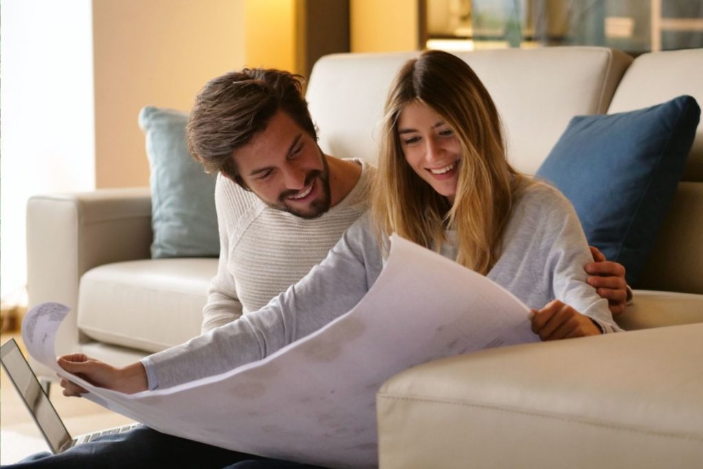 un homme et une femme sont assis par terre et regardent un agenda