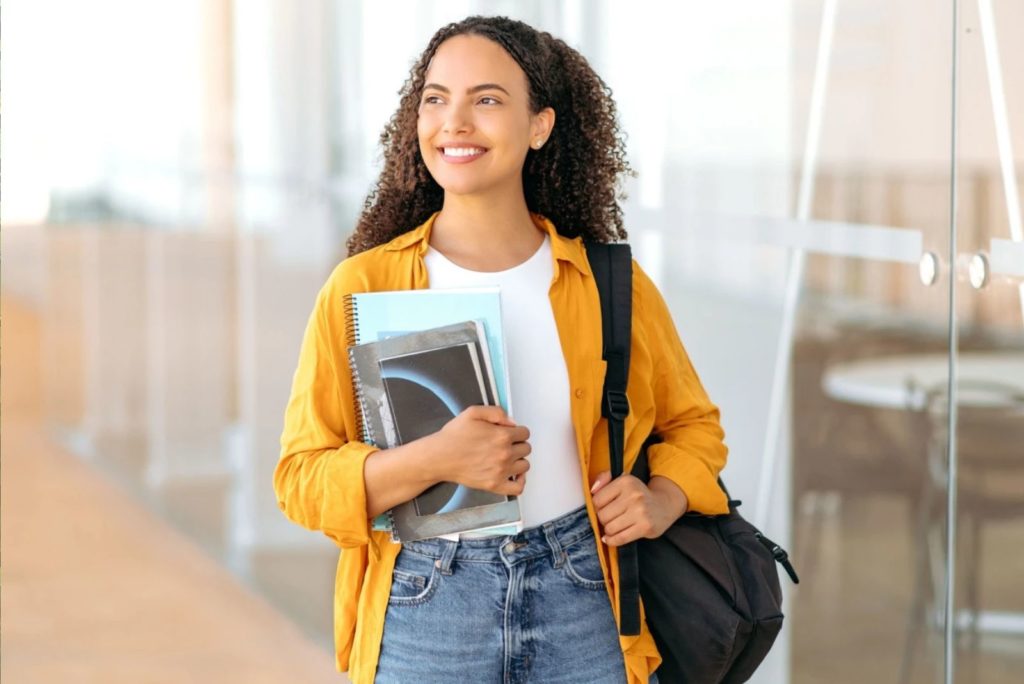 une belle fille avec un sac à dos et des livres à la main