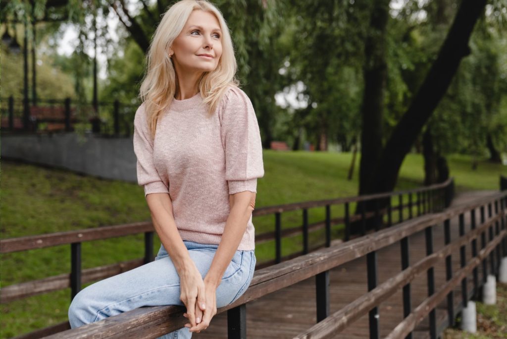 une belle fille est assise sur un pont en bois