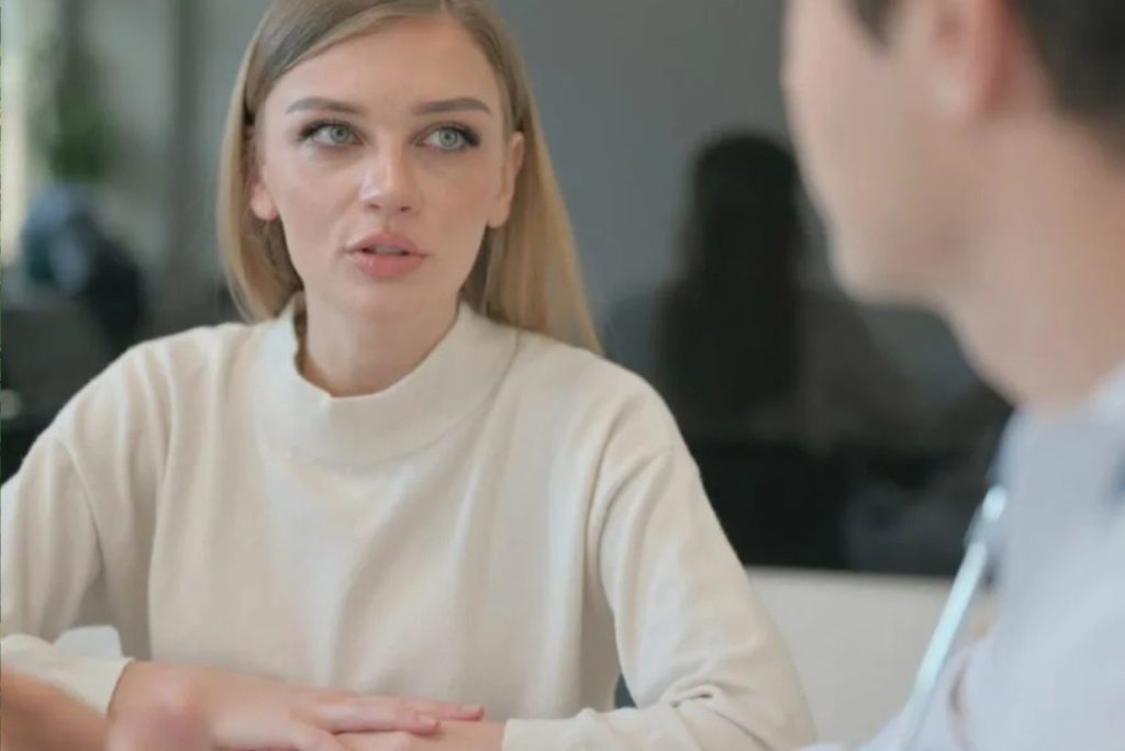 une femme aux cheveux blonds parle à un homme