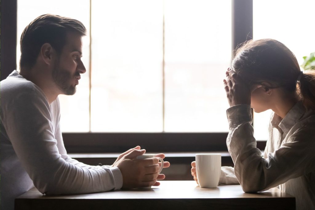 une fille déçue est assise à table avec un homme et ils parlent