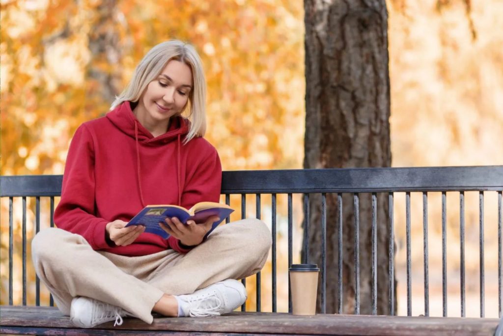 une fille est assise sur un banc et lit un livre