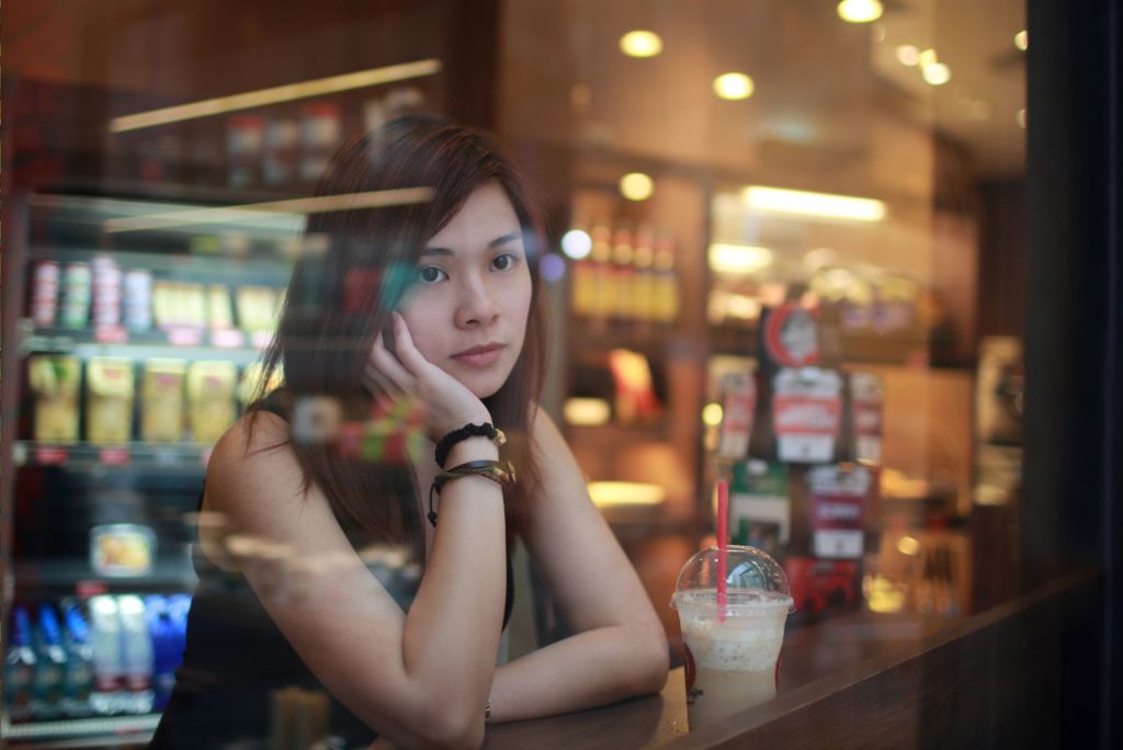 une fille pensive est assise au bar et boit du café