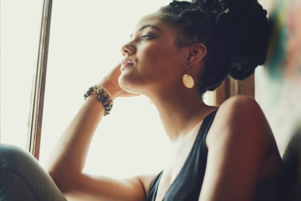 une fille pensive est assise près de la fenêtre