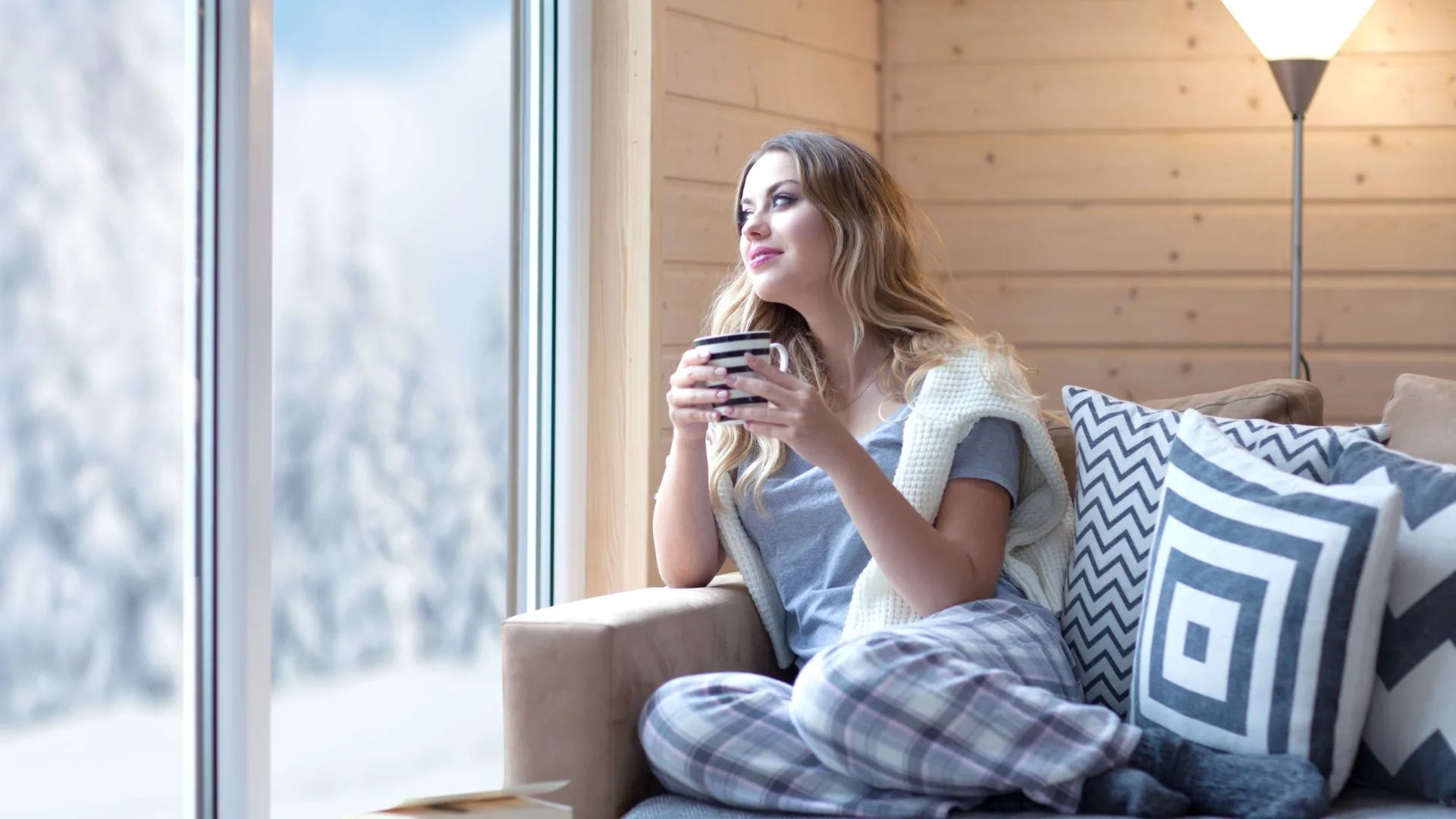 la fille est assise sur le canapé avec une tasse à la main