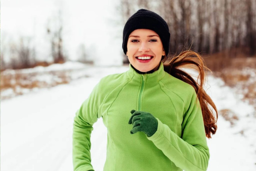 fille souriante court dans la neige